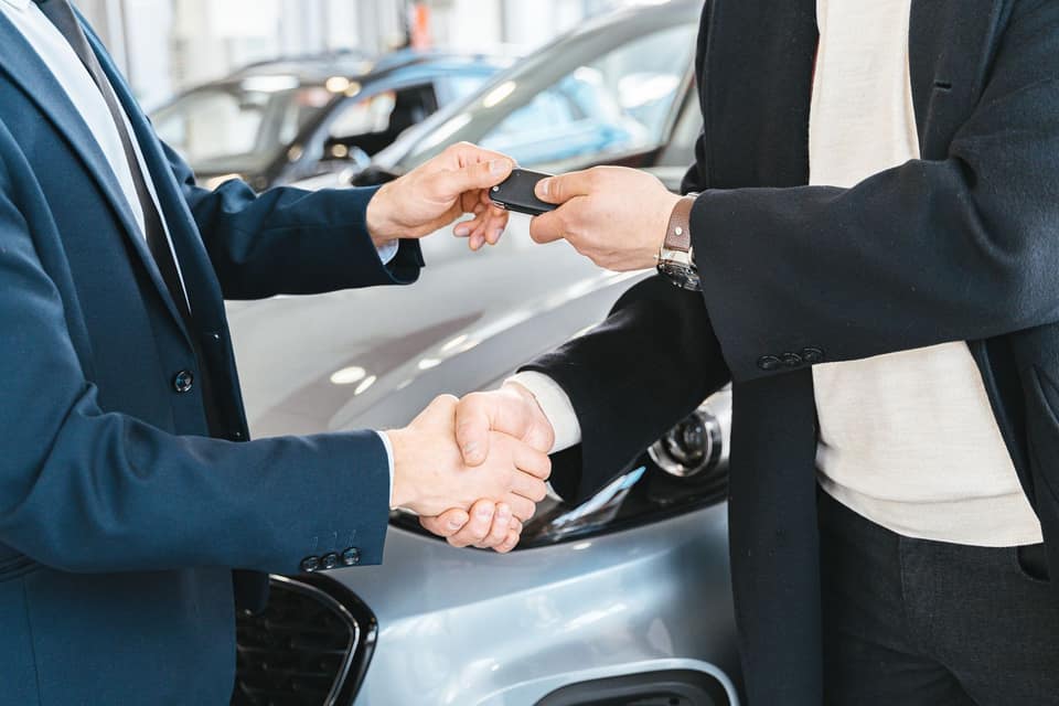 Comprador y vendedor se dan la mano mientras se entregan las llaves de un coche