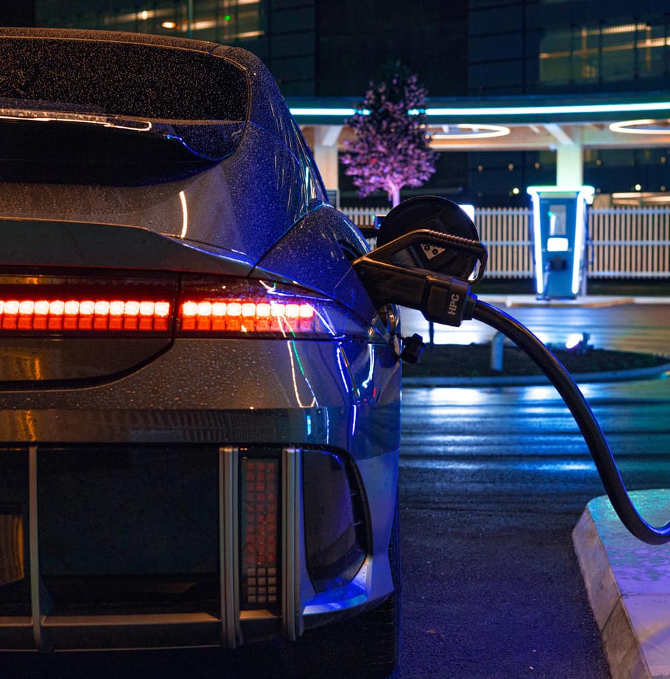 Un Hyundai Ioniq 6 enchufado a un punto de carga de noche