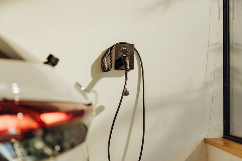 Coche eléctrico aparcado junto a un cargador de pared en una vivienda