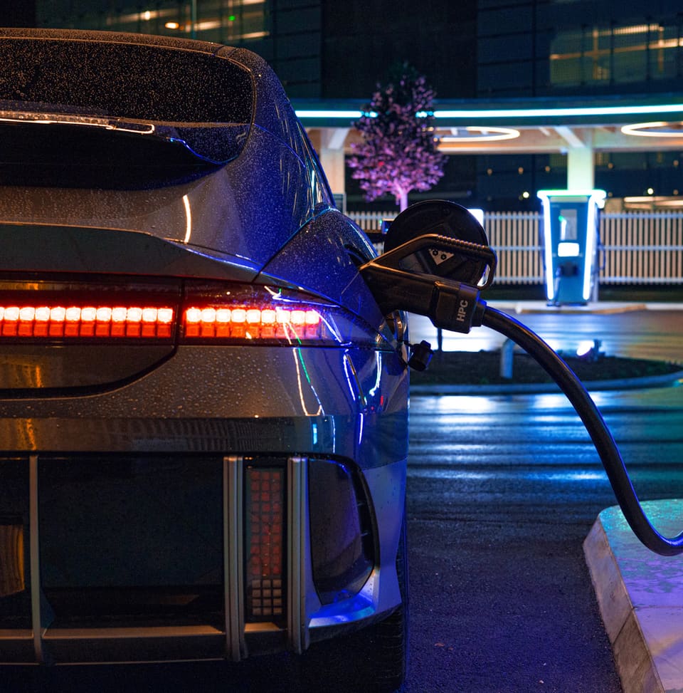 Un Hyundai Ioniq 6 enchufado a un punto de carga de noche